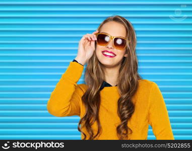 people, summer and fashion concept - happy young woman or teen girl in casual clothes and sunglasses over blue ribbed background. happy young woman or teen girl in casual clothes