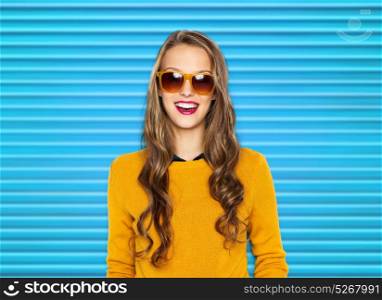people, summer and fashion concept - happy young woman or teen girl in casual clothes and sunglasses over blue ribbed background. happy young woman or teen girl in casual clothes