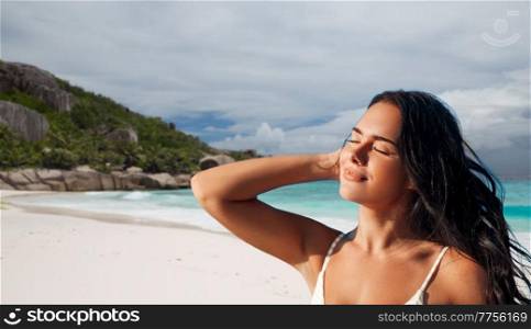 people, summer and swimwear concept - happy beautiful young woman in bikini swimsuit over tropical beach background in french polynesia. beautiful young woman in bikini swimsuit on beach