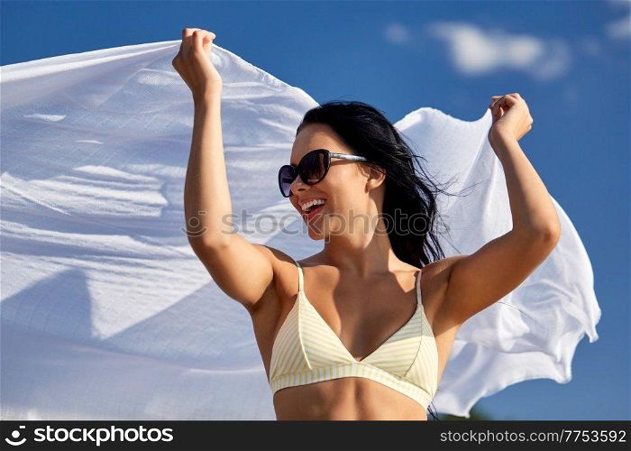 people, summer and swimwear concept - happy smiling young woman in bikini swimsuit with cover-up over blue sky. woman in bikini swimsuit with cover-up over sky