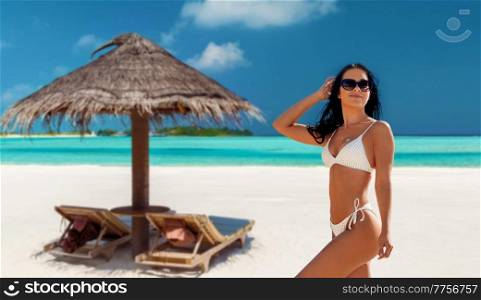 people, summer and swimwear concept - happy smiling young woman in bikini swimsuit over tropical beach background in french polynesia. smiling young woman in bikini swimsuit on beach