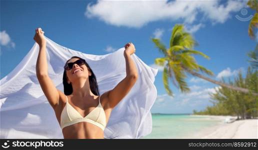 people, summer and swimwear concept - happy smiling young woman in bikini swimsuit with cover-up over tropical beach background in french polynesia. woman in bikini swimsuit with cover-up over sky