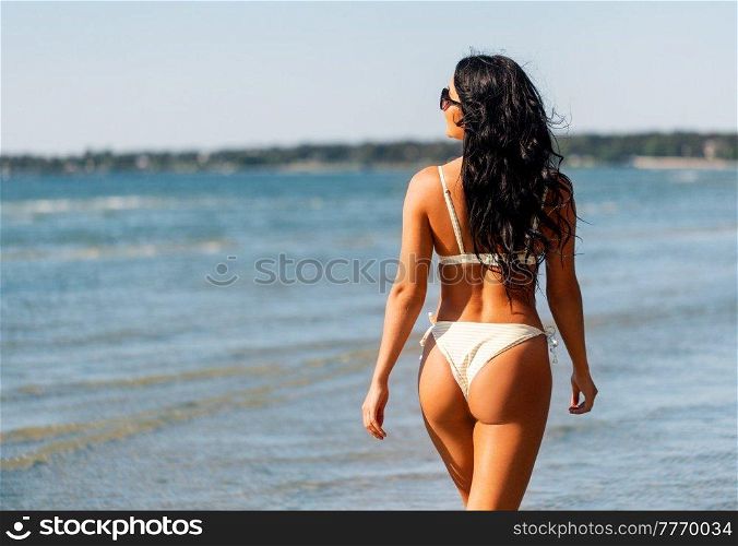 people, summer and swimwear concept - happy smiling young woman in bikini swimsuit on beach. happy young woman in bikini swimsuit on beach