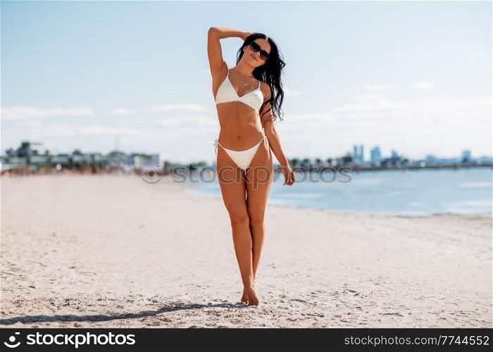 people, summer and swimwear concept - happy young woman in bikini swimsuit on beach. happy young woman in bikini swimsuit on beach