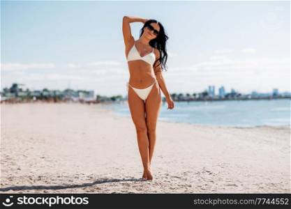 people, summer and swimwear concept - happy young woman in bikini swimsuit on beach. happy young woman in bikini swimsuit on beach