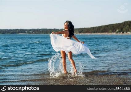 people, summer and swimwear concept - woman in bikini swimsuit with pareo on beach. woman in bikini swimsuit with pareo on beach