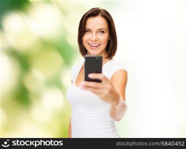 people, summer and technology concept - young woman taking selfie with smartphone over green natural background