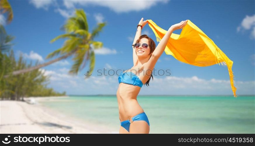 people, summer holidays and vacation concept - beautiful woman in bikini and sunglasses with pareo over exotic tropical beach with palm trees background