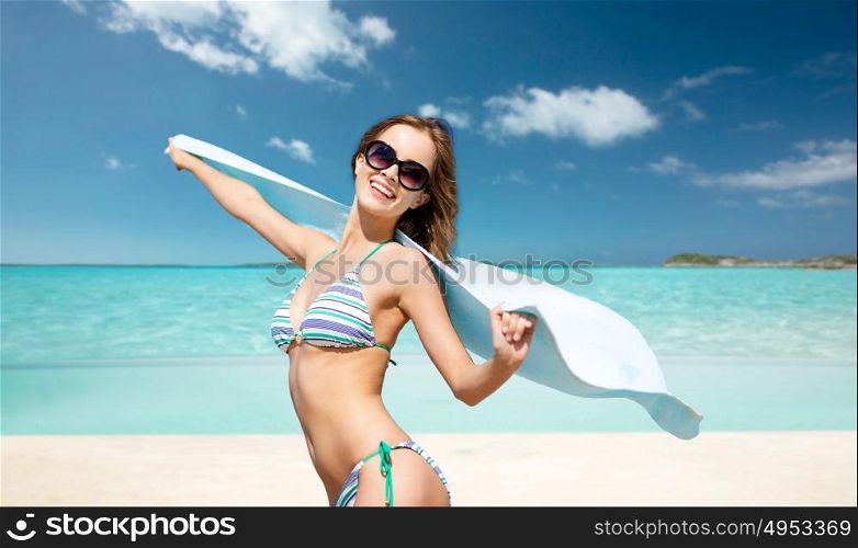 people, summer holidays and vacation concept - beautiful woman in bikini and sunglasses with towel over exotic tropical beach background. woman in bikini and sunglasses with towel on beach