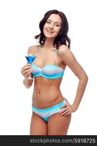 people, summer holidays, celebration, drinks and beach concept - happy young woman in bikini swimsuit drinking cocktail at party