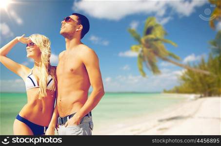 people, summer holidays, travel and vacation concept - happy couple over exotic tropical beach with palm trees background