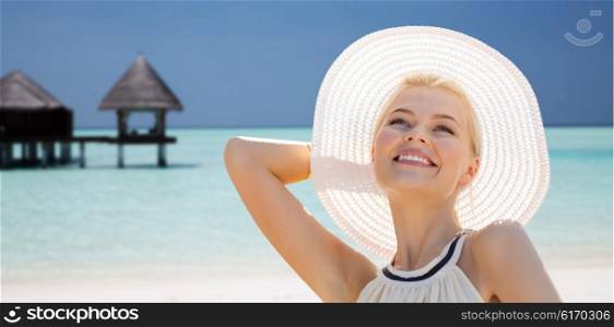people, summer holidays, travel, tourism and vacation concept - beautiful woman in sun hat enjoying summer over maldives beach with bungalow background