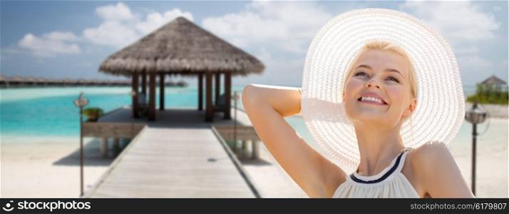 people, summer holidays, travel, tourism and vacation concept - beautiful woman in sun hat enjoying summer over maldives beach with bungalow background
