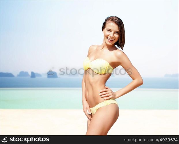 people, summer holidays, vacation and travel concept - happy young woman posing in bikini swimsuit hands over sea and infinity edge pool background. happy woman in bikini swimsuit over edge pool