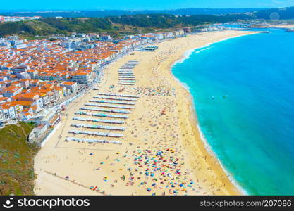 People sunbathing at the ocean beach in a summer day. Nazare, Portugal
