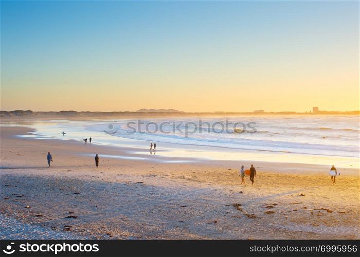 People, surfers walking by the beach at sunset. Baleal, Portugal
