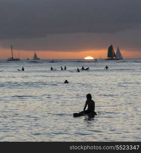 People surfing in the ocean at sunset, Waikiki, Honolulu, Oahu, Hawaii, USA