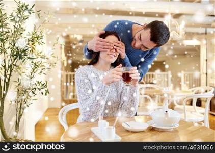 people, surprise and dating concept - happy couple drinking tea at cafe or restaurant