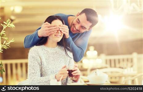 people, surprise and dating concept - happy couple drinking tea at cafe or restaurant. happy couple drinking tea at cafe