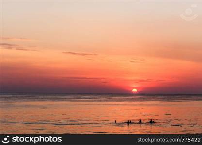 People swimming in the sea at sunset. Bang Tao beach, Phuket, Thailand