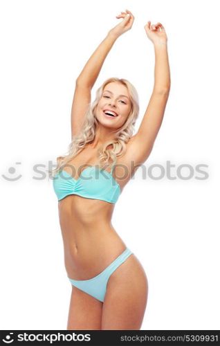 people, swimwear and summer concept - happy smiling young woman in bikini swimsuit with raised hands. happy smiling young woman in bikini swimsuit