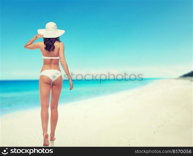 people, swimwear, beauty, travel and summer concept - young woman in white bikini swimsuit from back over beach background