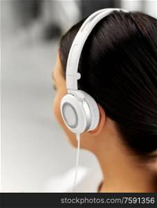 people, technology and audio equipment concept - close up of woman in headphones listening to music. close up of woman in headphones listening to music