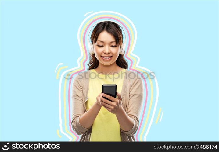 people, technology and audio equipment concept - happy asian young woman in headphones listening to music on smartphone over blue background with glowing lines. asian woman in headphones listening to music