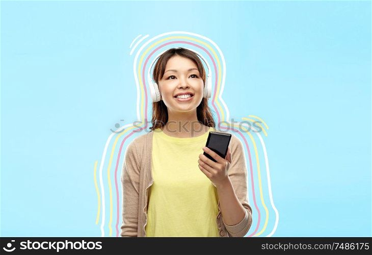 people, technology and audio equipment concept - happy asian young woman in headphones listening to music on smartphone over blue background with glowing lines. asian woman in headphones listening to music