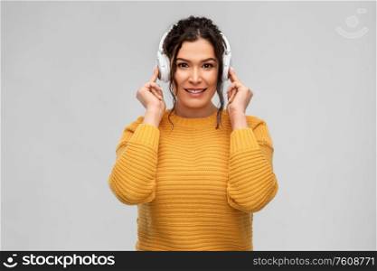 people, technology and audio equipment concept - happy smiling young woman with pierced nose in headphones listening to music over grey background. happy woman in headphones listening to music