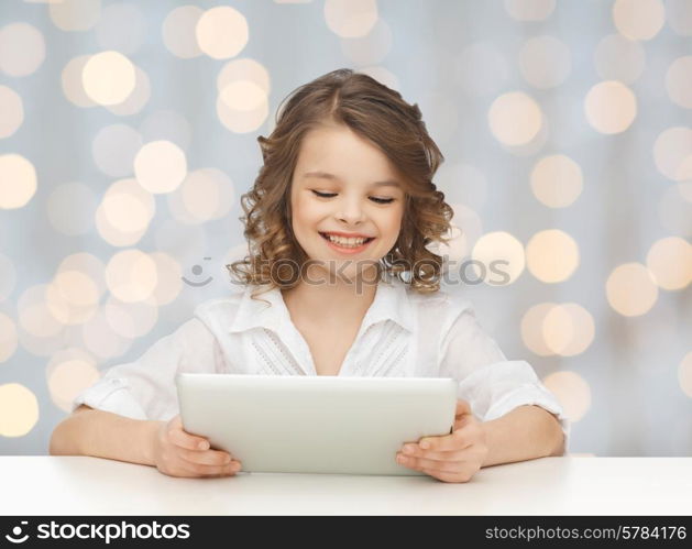 people, technology and children concept - happy smiling girl with tablet pc computer over holidays lights background