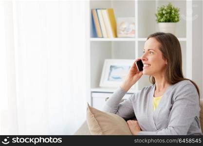 people, technology and communication concept - happy middle-aged woman calling on smartphone at home. happy woman calling on smartphone at home