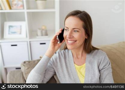 people, technology and communication concept - happy middle-aged woman calling on smartphone at home. happy woman calling on smartphone at home. happy woman calling on smartphone at home