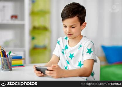 people, technology and communication concept - happy smiling boy with smartphone at home. happy boy with smartphone at home