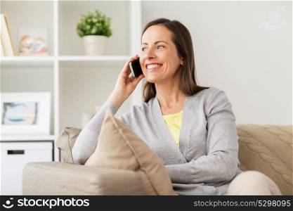 people, technology and communication concept - happy woman calling on smartphone at home. happy woman calling on smartphone at home