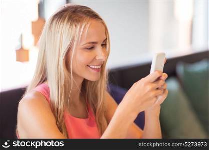 people, technology and communication concept - happy woman with smartphone networking at restaurant. happy woman with smartphone at restaurant