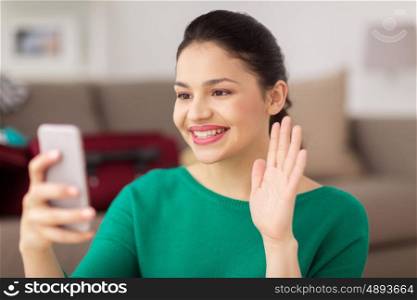people, technology and communication concept - happy young woman with smartphone taking selfie or having video call at home
