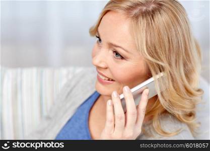 people, technology and communication concept - smiling woman calling on smartphone at home