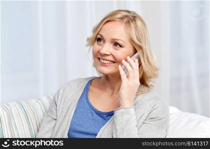 people, technology and communication concept - smiling woman calling on smartphone at home