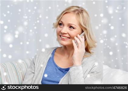 people, technology and communication concept - smiling woman calling on smartphone at home over snow