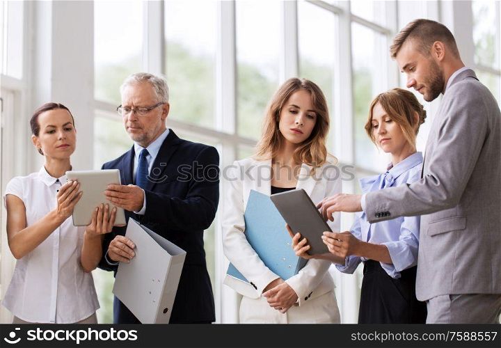 people, technology and corporate concept - business team with tablet pc computers and folders at office. business team with tablet pc and folders at office