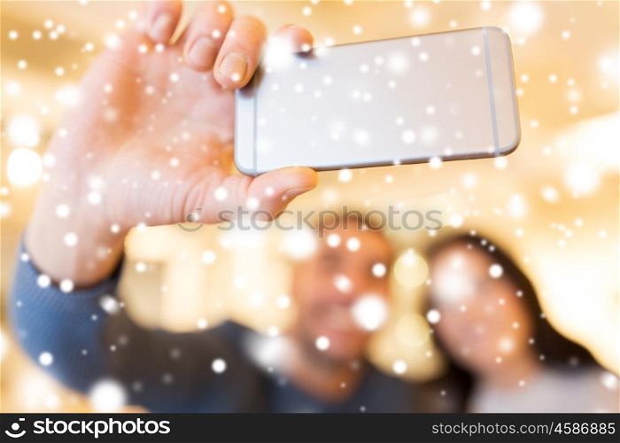 people, technology and dating concept - close up of happy couple taking smartphone selfie at cafe or restaurant