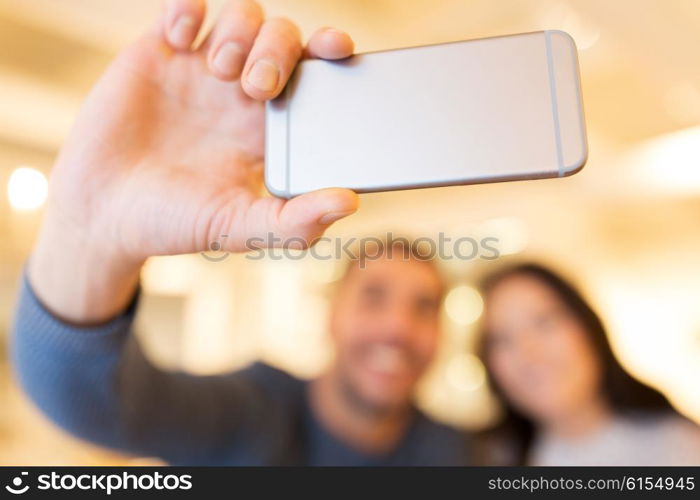 people, technology and dating concept - close up of happy couple taking smartphone selfie at cafe or restaurant