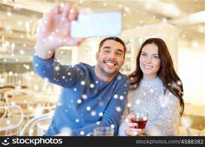 people, technology and dating concept - happy couple taking smartphone selfie and drinking tea at cafe or restaurant