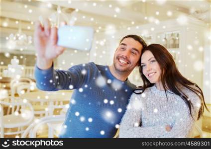 people, technology and dating concept - happy couple taking smartphone selfie at cafe or restaurant