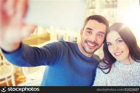 people, technology and dating concept - happy couple taking smartphone selfie at cafe or restaurant. couple taking smartphone selfie at cafe restaurant