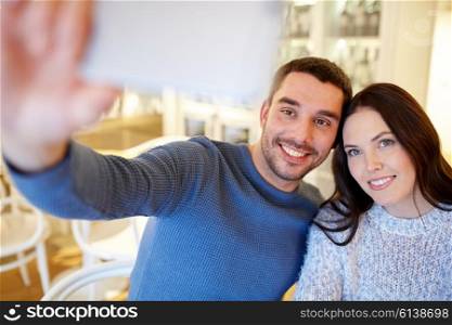 people, technology and dating concept - happy couple taking smartphone selfie at cafe or restaurant