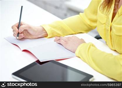 people, technology and education concept - close up of female hands with tablet pc computer writing to notebook at school