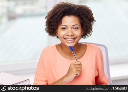 people, technology and education concept - happy african american young woman sitting at table with laptop computer and books at home