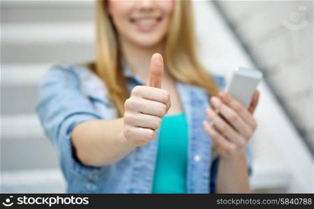 people, technology and internet concept - close up of happy teenage girl hands with smartphone showing thumbs up